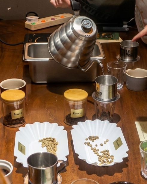 Coffee brewing setup with various equipment on a table, people around